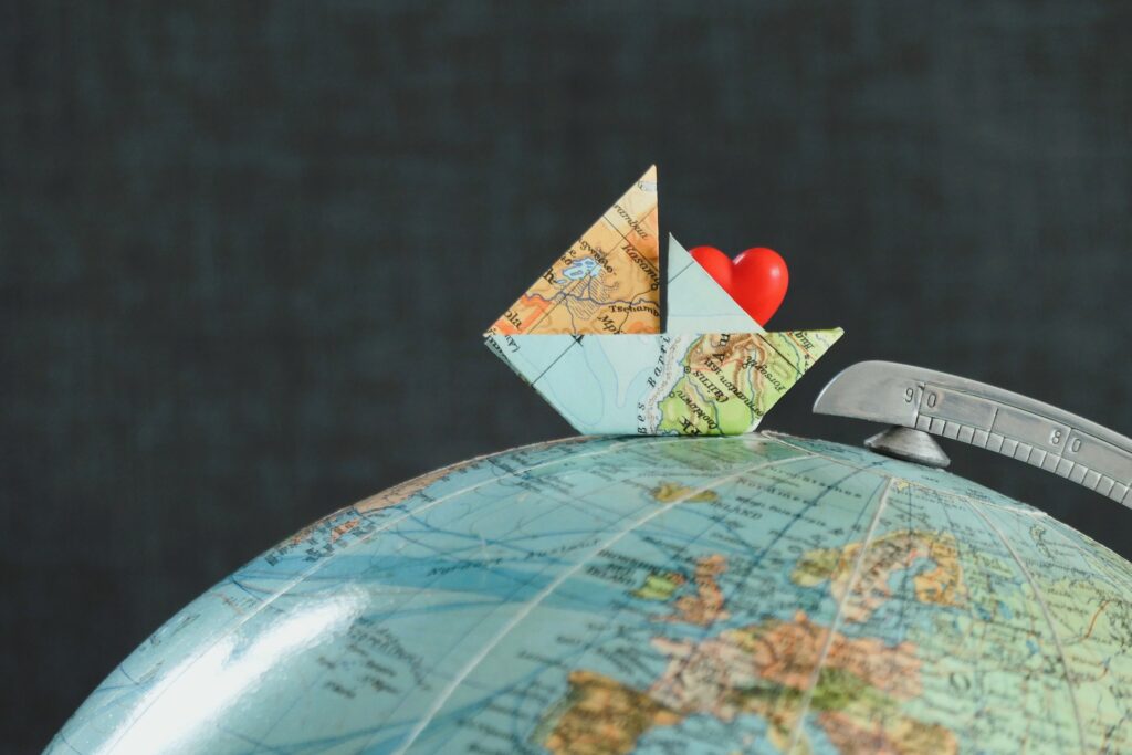 A paper ship travelling on a globe, symbolising global-reach.