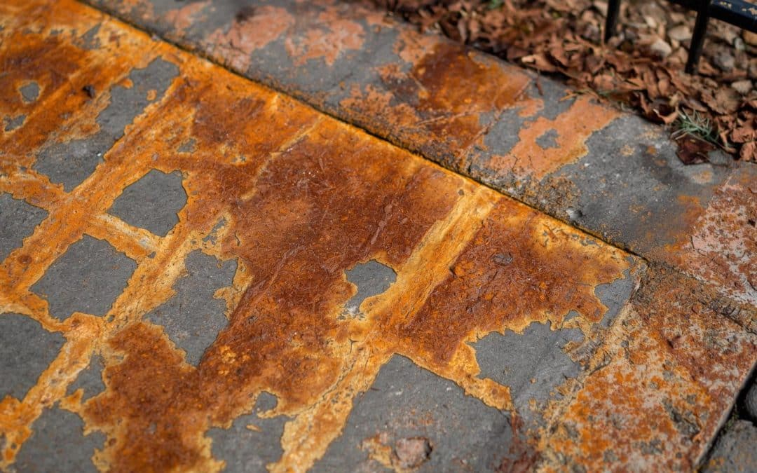 Bore water iron oxide stains on concrete driveway, brick pavers, and metal fencing showing orange-brown rust discoloration
